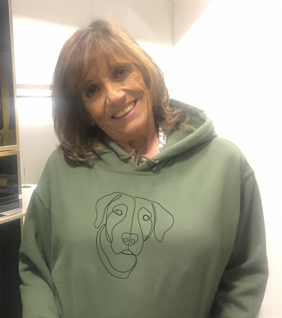 Woman wearing her green custom embroidered hoodie with line art of her dog.