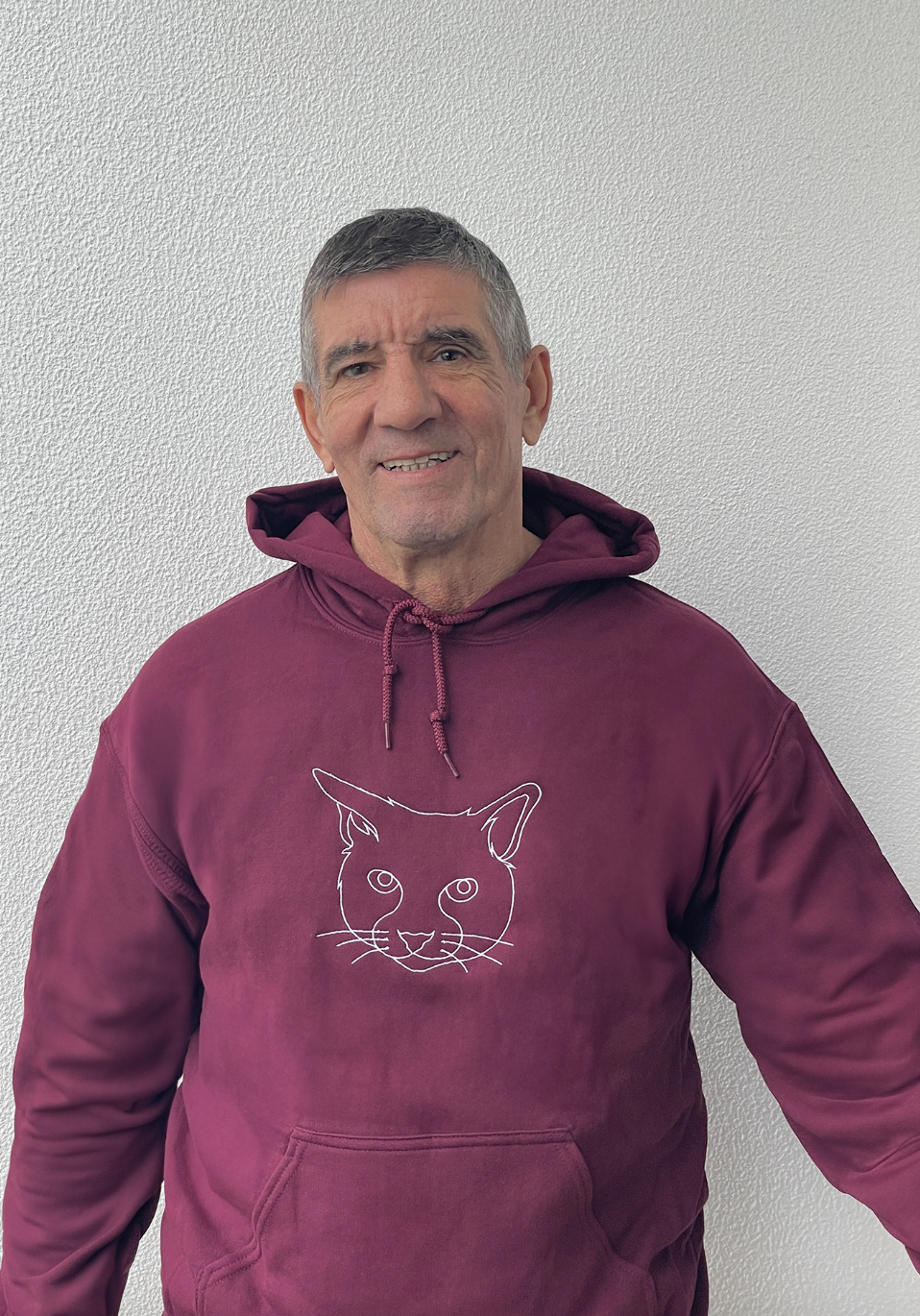 Man wearing his custom embroidered hoodie with line art of his cat.