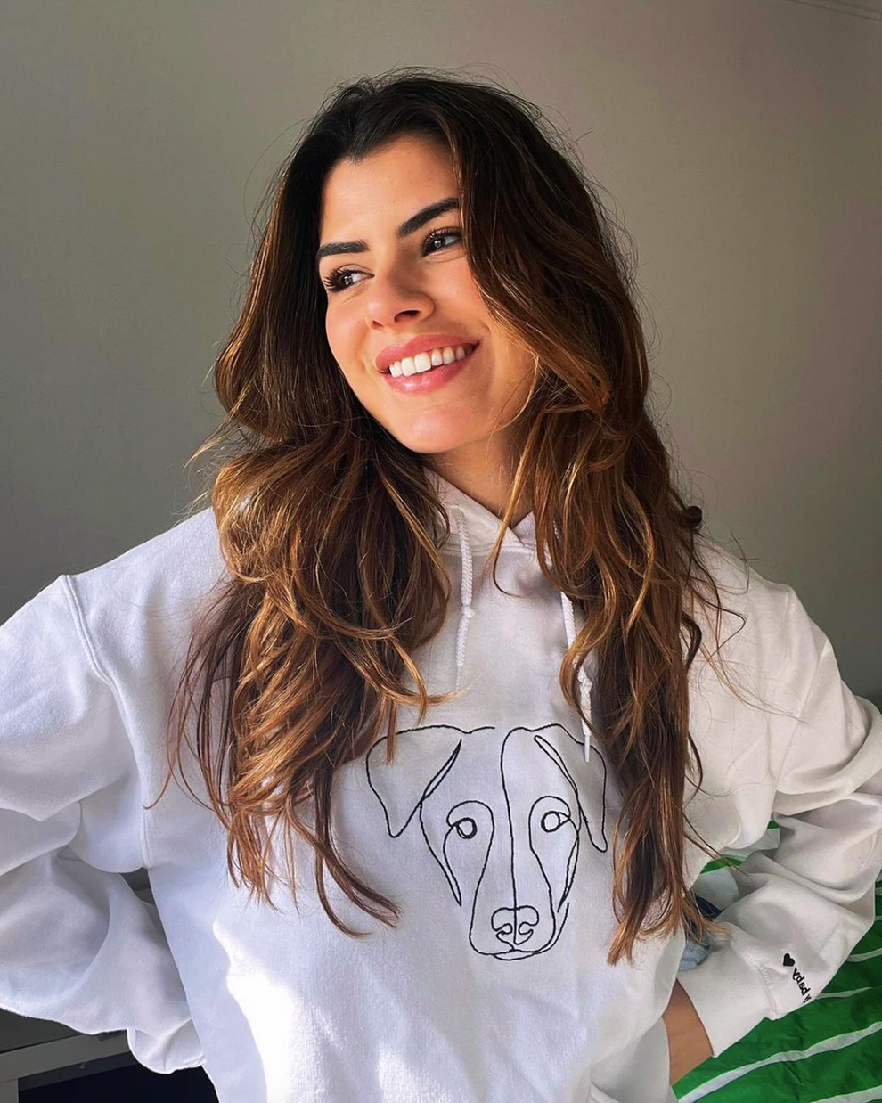 Girl wearing white custom embroidered hoodie with handmade line art of her dog portrait.
