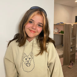 Kid wearing her custom embroidered hoodie with line art of her dog.