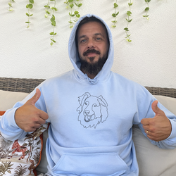 Man wearing his custom embroidered hoodie with line art of his dog holding a ball on his mouth.