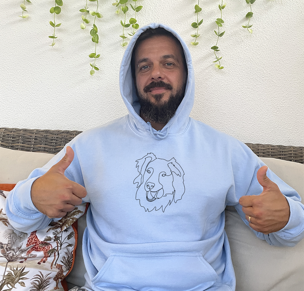 Man wearing his custom embroidered hoodie with line art of his dog holding a ball on his mouth.